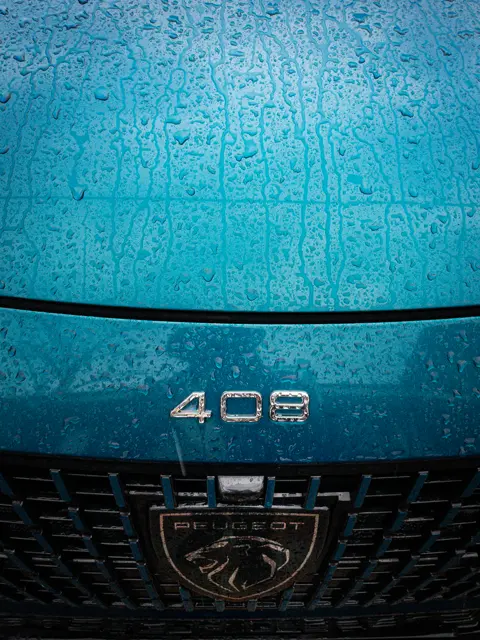 The teal bonnet of a Peugeot 408 in the rain